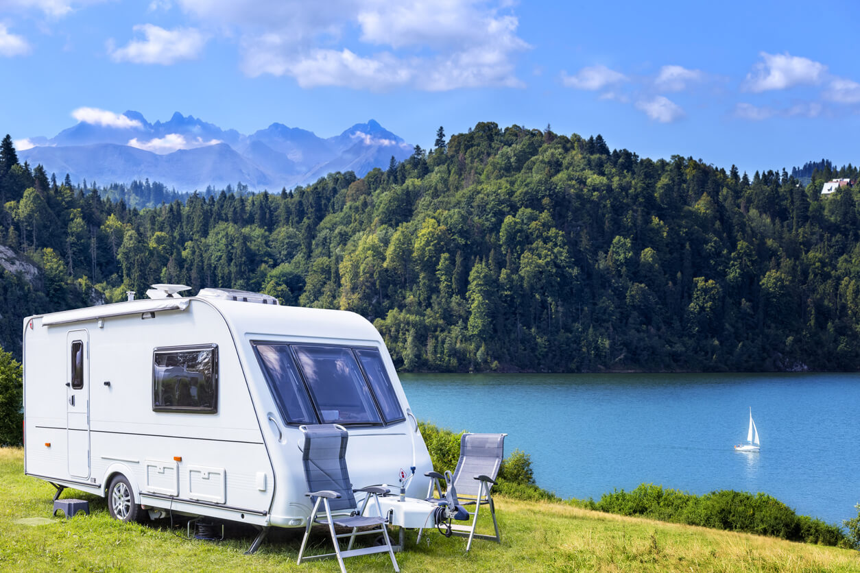 modern camper parked in front of a lake modern camper parked in front of a lake